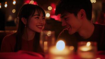 A couple shares a joyful moment during a candlelit dinner, surrounded by warm lighting and vibrant decorations. Their smiles indicate a deep connection as they gaze into each other's eyes. photo