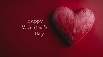A bright red heart shaped decoration rests on a deep red background. Bold white text wishes viewers a happy Valentine's Day, creating a romantic and festive atmosphere perfect for the holiday. photo