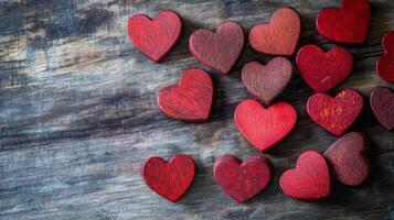 Small red hearts are scattered across a rustic wooden surface, creating a warm and inviting atmosphere ideal for romantic occasions or festive events. The vibrant colors add a cheerful touch. photo