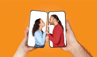A couple interacts through their smartphones, expressing love and affection. Their hands hold phones displaying images of each other, symbolizing modern connections. photo