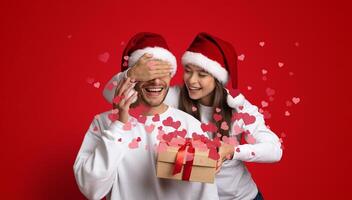 A couple joyfully shares a moment while celebrating Valentine's Day, with playful gestures and a surprise gift. They express their affection in a lively, festive atmosphere filled with hearts. photo