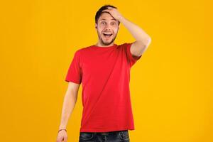 Omg, Wow. Portrait of young shocked handsome guy with open mouth holding hand on his head, looking at camera in amazement and with surprised facial expression, standing isolated over blue background photo