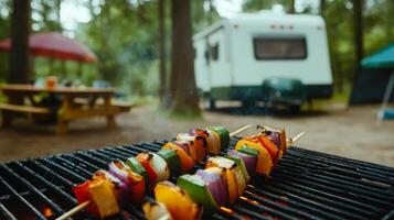 Colorful vegetable skewers sizzle over a grill while camping in a forest. A trailer is visible in the background, and picnic tables offer a cozy outdoor gathering space. photo
