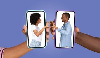 Two hands hold smartphones displaying a couple expressing affection through a virtual heart gesture. The vibrant background emphasizes their loving interaction, bridging distance with technology. photo