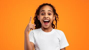Hey, I Have Great Idea. Portrait of emotional African American girl pointing index finger up, thinking and finding inspiration or solution. Excited curly black kid with open mouth, studio wall, banner photo