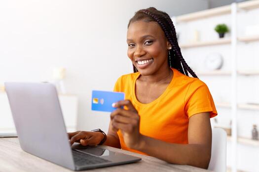 comercio electrónico concepto. milenario africano americano dama utilizando crédito tarjeta para remoto pago, compras en línea vía ordenador portátil a hogar. joven negro mujer adquisitivo bienes en web almacenar, adentro foto