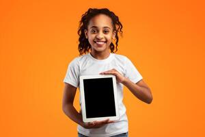 Great Application. Portrait Of Smiling African American Girl Holding And Showing Digital Tablet With Empty Screen For Mock up, Recommending New App Posing Standing Over Yellow Studio Background photo