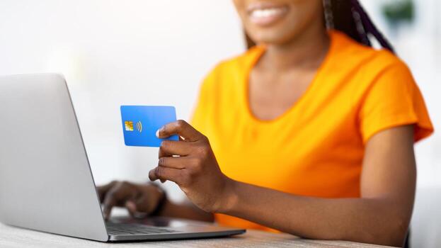 sin efectivo pago. irreconocible negro mujer participación crédito tarjeta, mecanografía en ordenador portátil ordenador personal, compras en línea desde hogar, de cerca. africano americano dama utilizando electrónico dinero a comprar bienes en web Tienda foto