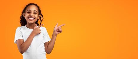 Check This. Portrait Of Positive Black Young Girl Pointing With Two Fingers Aside At Copy Space On Yellow Background, African American Kid Demonstrating Free Place For Your Design Or Advertisement photo
