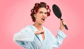 Angry Housewife Raising Frying Pan Shouting In Rage Looking At Camera Posing On Yellow Background. Studio Shot photo
