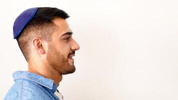 Profile side view headshot portrait of handsome smiling jewish guy posing at studio, looking aside, wearing kippah, posing isolated on light white studio background, copy free space, advert banner photo