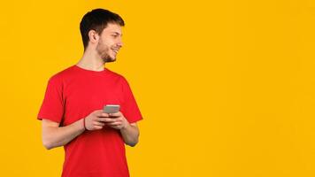 Communication And Technology. Portrait of smiling man using his smartphone standing isolated over blue studio background, looking away at copy space, holding gadget. Guy chatting online photo