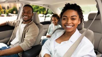 Happy Family In Car Smiling To Camera Sitting In Seats Having Ride Across City. Parents And Daughter Driving New Automobile Travelling On Summer Vacation. Selective Focus photo