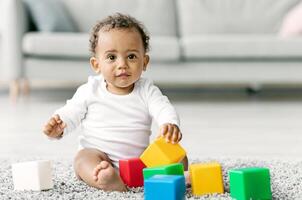 Adorable Black Infant Baby Playing With Stacking Building Blocks At Home While Sitting On Carpet In Living Room, Portrait Of Cute African American Child Using Colorful Constructor Toys, Copy Space photo