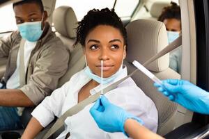 Covid-19 Diagnostic. Black Family Of Three Getting Tested For Coronavirus With Nasal PCR Test Sitting In Automobile, Wearing Protective Face Masks. Covid Pandemic Outbreak Concept photo