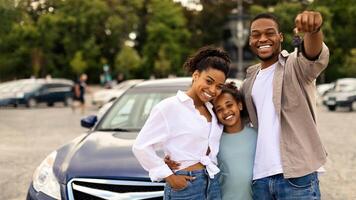 Joyful Black Family Showing New Car Key Posing Standing Near Luxury Auto Outdoor, Smiling To Camera. Parents And Daughter Celebrating Buying Vehicle. Automobile Leasing And Ownership photo