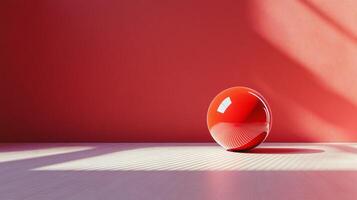 A red ball is sitting on a table in front of a red wall photo