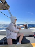 Young woman sailing on a boat under a clear blue sky while adjusting the sail photo
