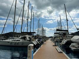Calm marina with sailboats docked under a partly cloudy sky in a serene setting photo