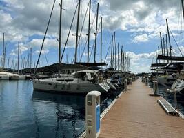 Sailboats docked in a sunny marina with clear blue skies and scattered clouds photo