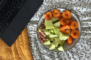 Fresh fruit platter on a cozy blanket beside a laptop in a relaxed setting photo