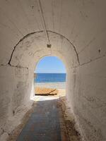 Archway leading to a serene beach view with wooden deck on sunny day photo