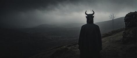 A man in a black cloak standing on a hill photo