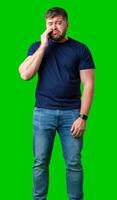 Man expressing frustration with tired eyes while standing in front of a bright green background photo