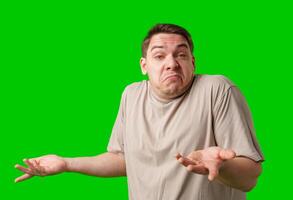 A man stands with arms crossed and a thoughtful expression in front of a green screen photo