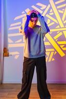 A young person stands with their hands on their head, looking down, in front of a wall with a projected pattern photo