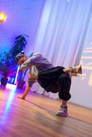 A dancer performs a breakdancing move in a studio with colorful lighting photo