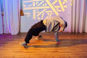 A dancer performs a breakdancing move in a studio with white curtains and a patterned light photo