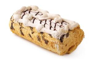 Delicious dessert log cake with cream frosting and chocolate drizzle served on a plain background photo