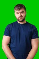 Man expressing confusion with crossed arms in front of a bright green background photo