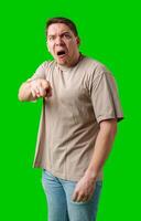 Man expressing anger and pointing in a plain t-shirt with a bright green background photo