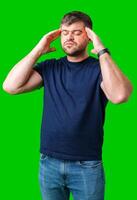 A man with closed eyes holds his head in a thoughtful pose against a bright green backdrop photo