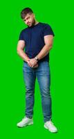 Man standing with a thoughtful expression in a casual outfit against a green background photo