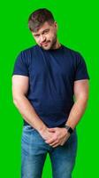 Man standing with a thoughtful expression in a casual outfit against a green background photo