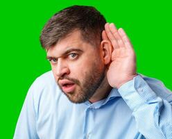 A man listening intently with a surprised expression in a bright green background photo