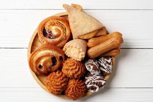 Assorted sweet pastries and baked goods on a wooden plate arranged for dessert enjoyment photo