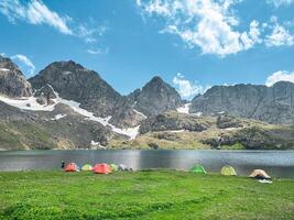 Camping tent by the lake in front of the mountain. photo