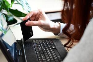 Engaging in Online Shopping With a Credit Card at a Desk Surrounded by Plants While Working From Home photo