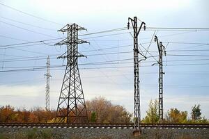 High-voltage power lines passing through a plowed field, on the background of a beautiful cloudy sky. photo