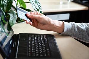 A woman is making a purchase online using a laptop and a credit card. photo