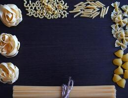 A close-up shot of a variety of pasta, including spaghetti, macaroni, and fettuccine, laid out on a burlap table runner. photo