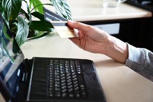 A close-up shot of a person holding a black credit card and making an online purchase. photo
