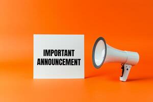 Important announcement message written on white card with a megaphone on orange background photo
