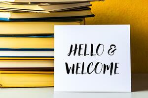 Hello and welcome message written on white card with stack of books photo