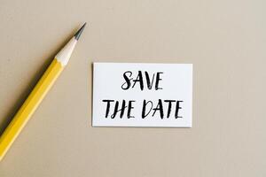 Save the date message written on a white card with pencil. Conceptual save the date symbol. Copy space. photo