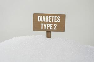 Diabetes type 2 message written on wooden sign on white background with sugar photo
